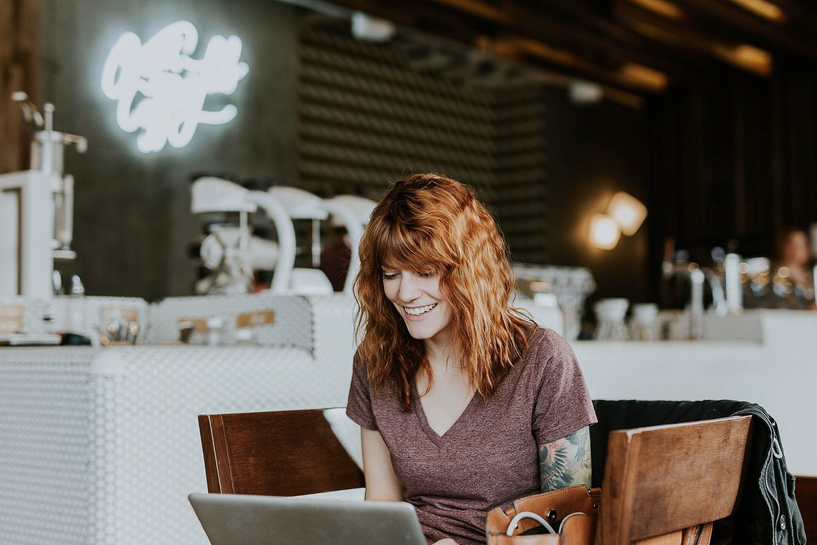 Woman smiling at her laptop in a cafe