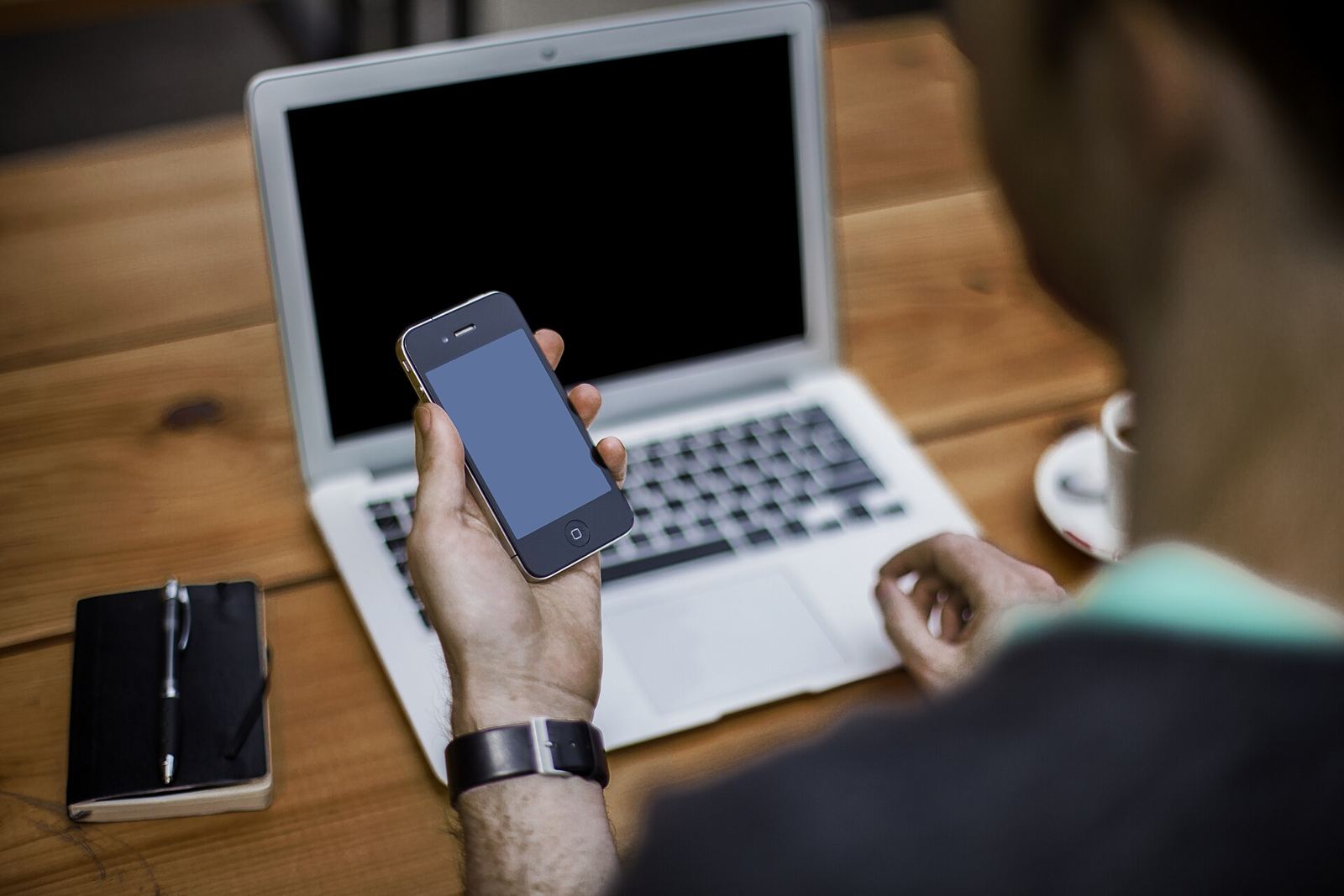 Person holding a phone in front of a laptop